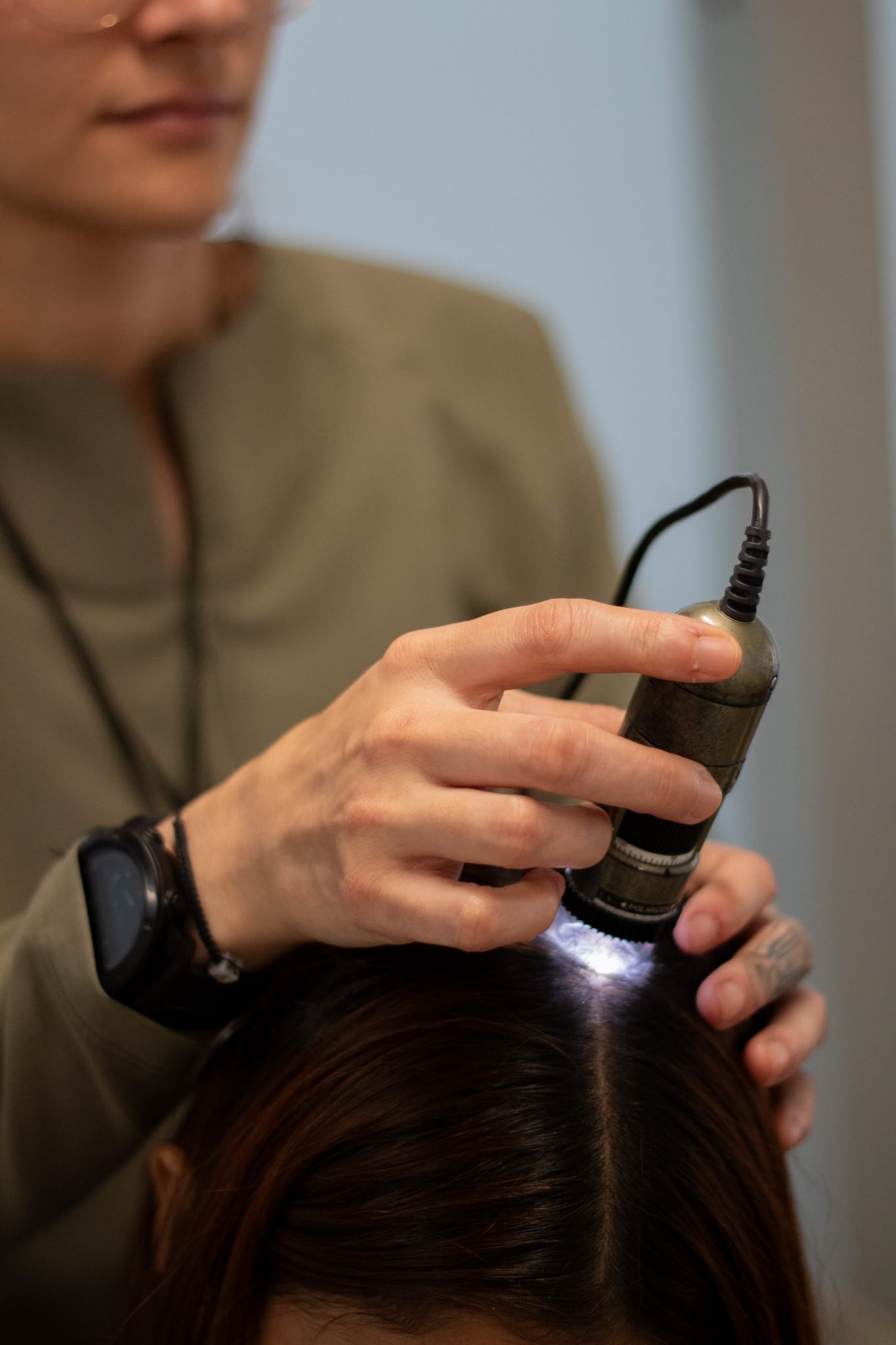 Especialista de HairLab revisando el cuero cabelludo de una persona con una cámara de aumento.